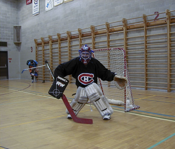 Photo d'Alain Cogliastro dans un gymnase intérieur, habillé en gardien de but de hockey